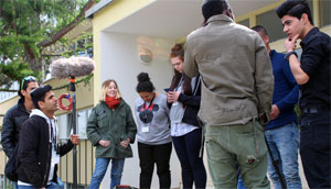 Junge Menschen stehen vor einem Haus und haben Kamera-Equipment in der Hand.