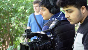 Drei junge Männer filmen etwas in der Natur.